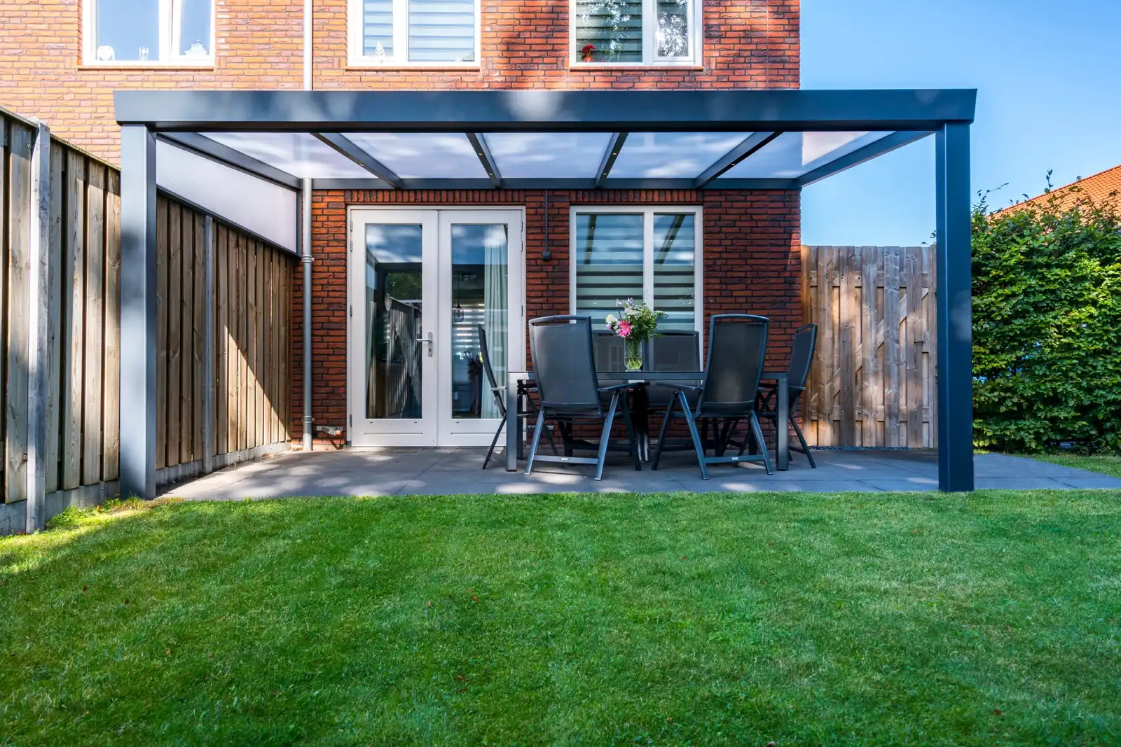 Deponti Giallo veranda with a glass roof, wall mounted above a patio and dining table