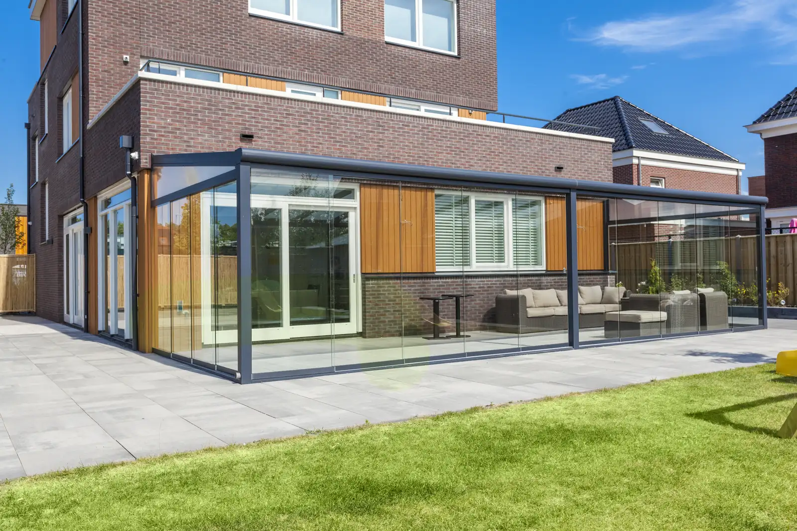 Fully enclosed glass veranda with sliding panels along the rear elevation of a house