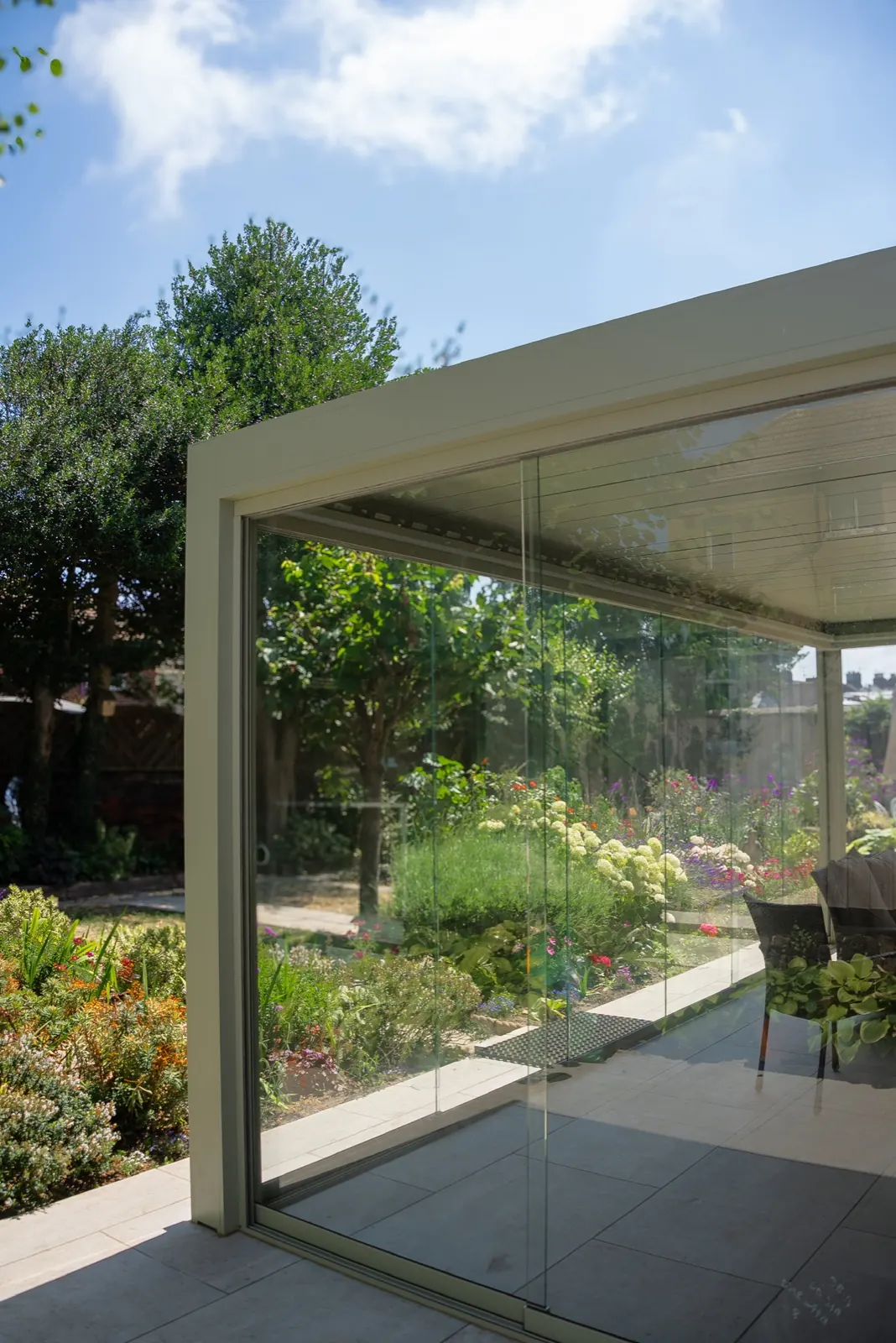 Aluminium veranda with glass sliding doors beside a flower garden