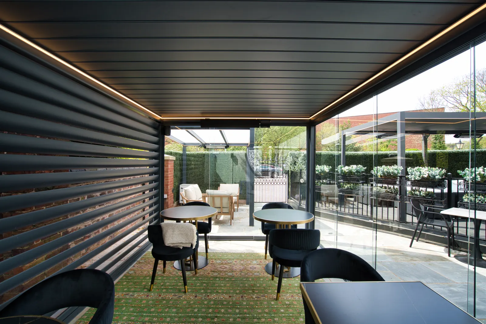 Louvred roof pergola with glass sides, louvred side panels and LED lighting over a dining area