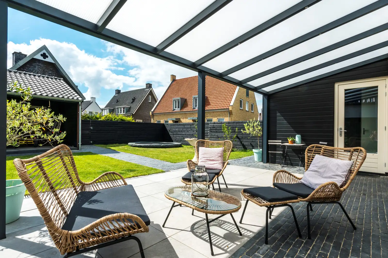 Veranda with a translucent roof over rattan seating on a paved patio