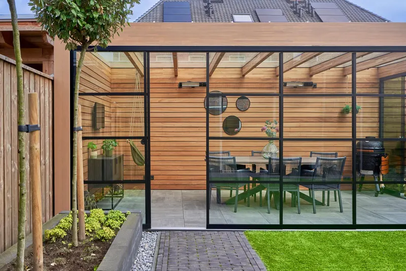 Deponti Fiano black framed glass sliding walls on a timber garden room with dining table