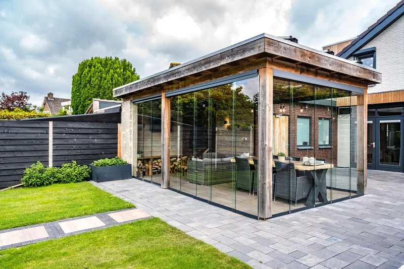 Deponti Fiano glass sliding walls fitted around a timber garden room beside a paved patio