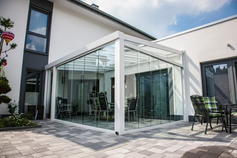 White Deponti Giallo veranda enclosed with glass sliding walls on a paved courtyard