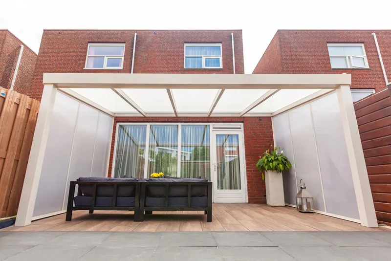 Cream Deponti Giallo veranda with opal side panels over a sofa on a decked patio