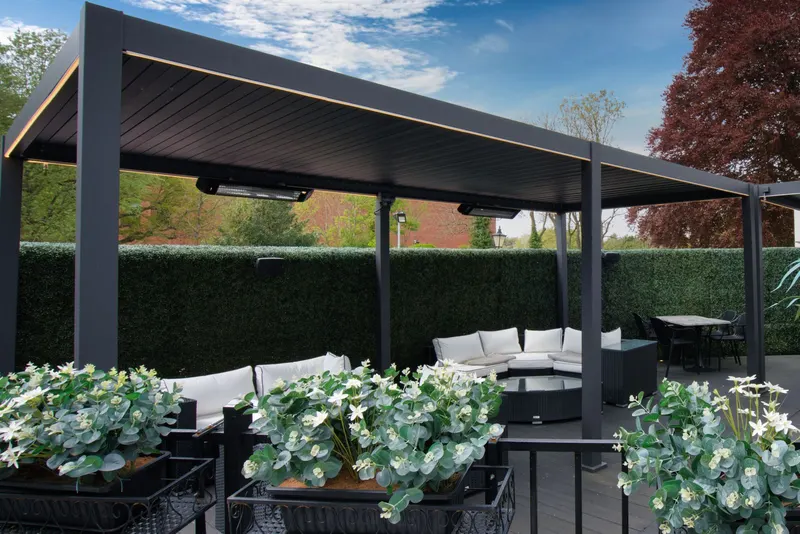 Two Deponti Pinela louvred pergolas over lounge seating on a terrace with planters