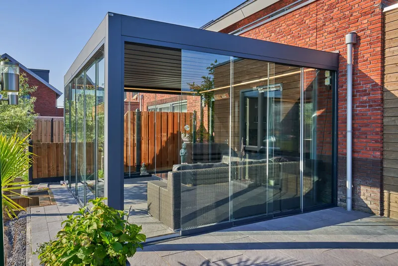 Deponti Pinela Deluxe with glass sliding walls on a paved terrace against a brick house