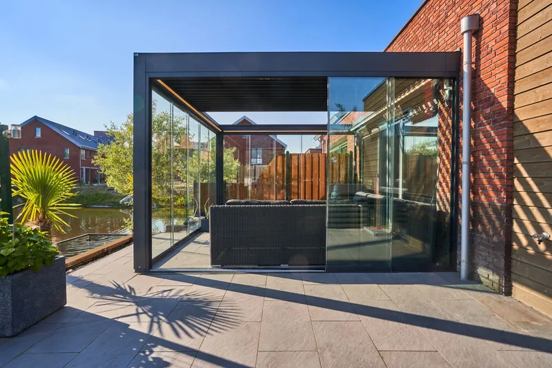 Deponti Pinela Deluxe glass room seen from the terrace, sofa inside and water beyond