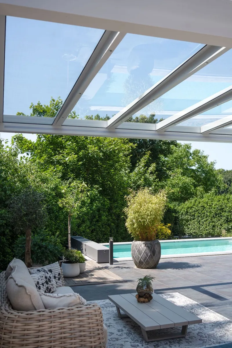 Deponti Pinela Glass roof over a wicker lounge set beside a swimming pool