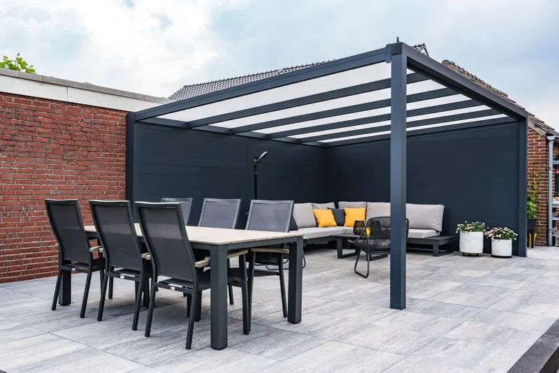 Deponti Ribolla anthracite wall panels behind a dining table and corner sofa on a paved terrace