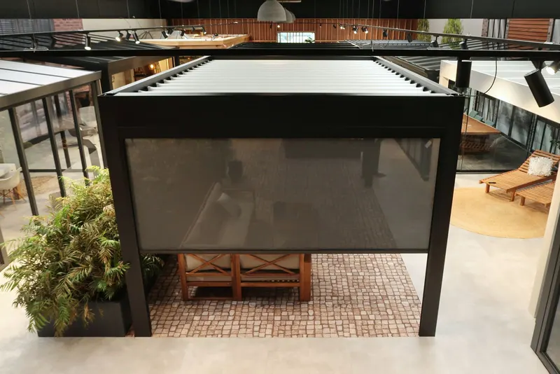 Deponti Screen lowered on the front of a louvred pergola with plants and outdoor sofa