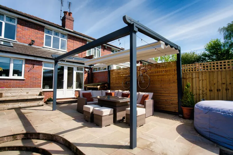 Deponti Verdeca pergola with fabric roof partly open over rattan sofas and stools