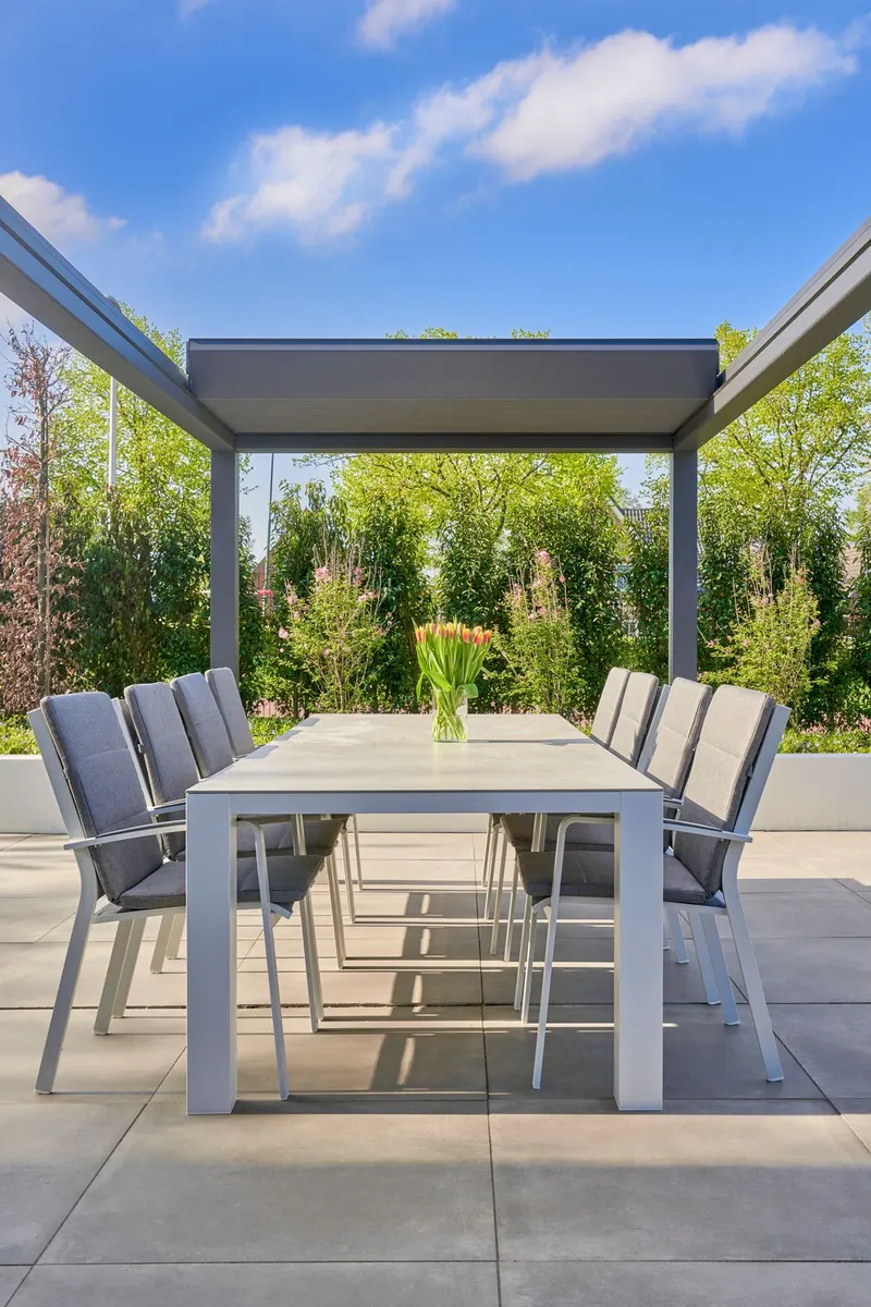 Deponti Pinela Deluxe with the roof panels retracted, open sky above a dining table on a paved terrace