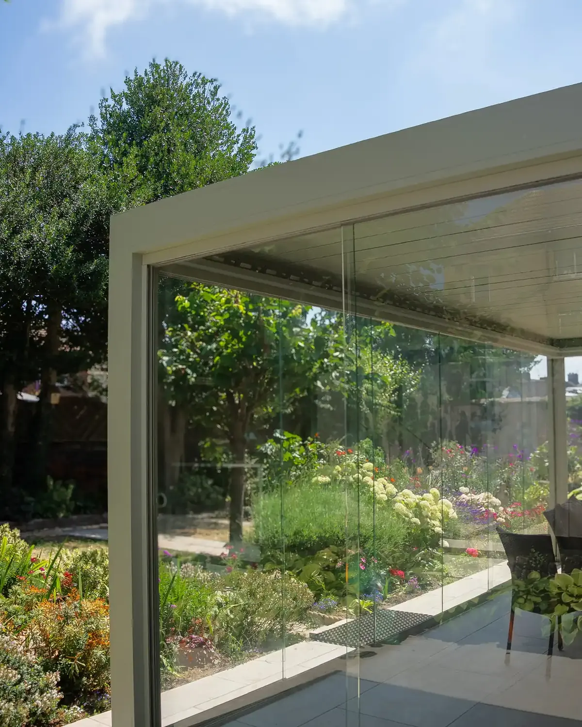 Aluminium veranda with glass sliding doors beside a flower garden